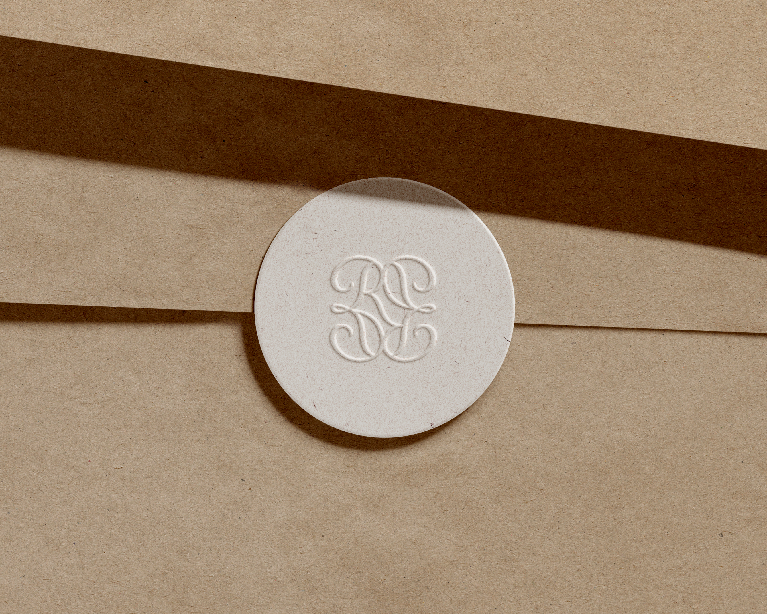 Round silver monogrammed seal on a brown paper background